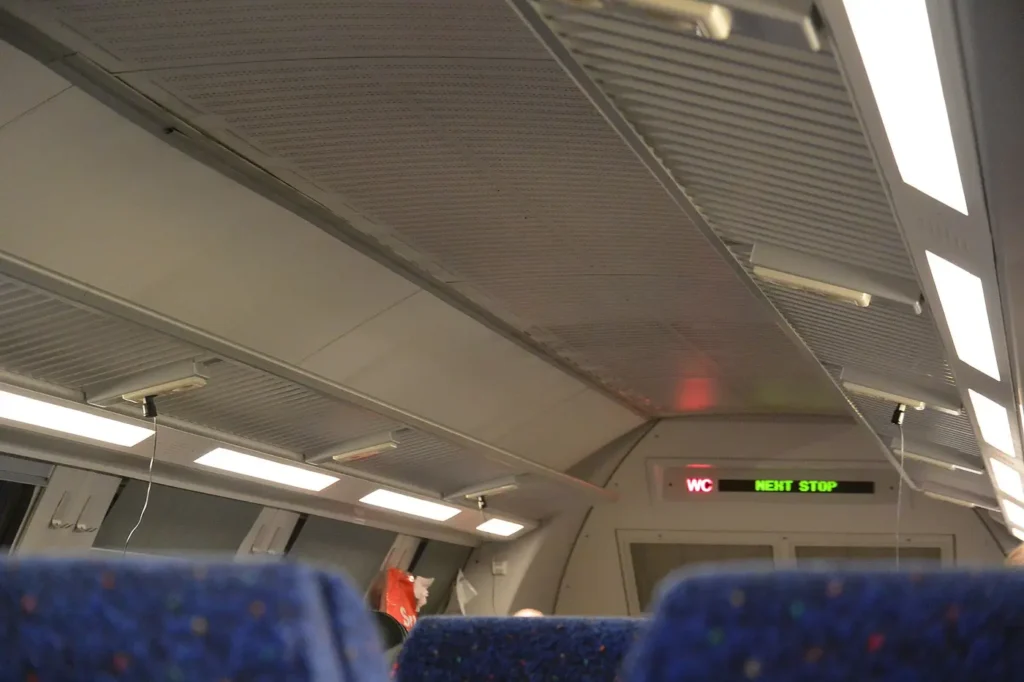 Travelers charging smartphones while riding an airport train